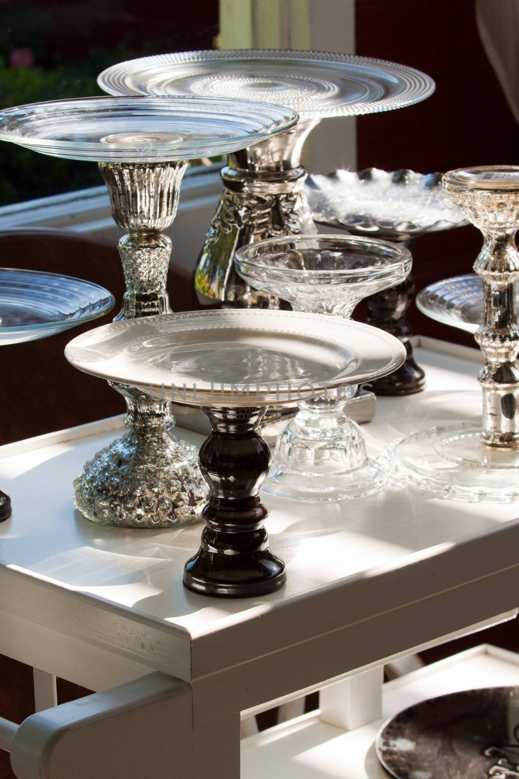 Plates stand upon footed holders for serving cakes at a wedding reception.