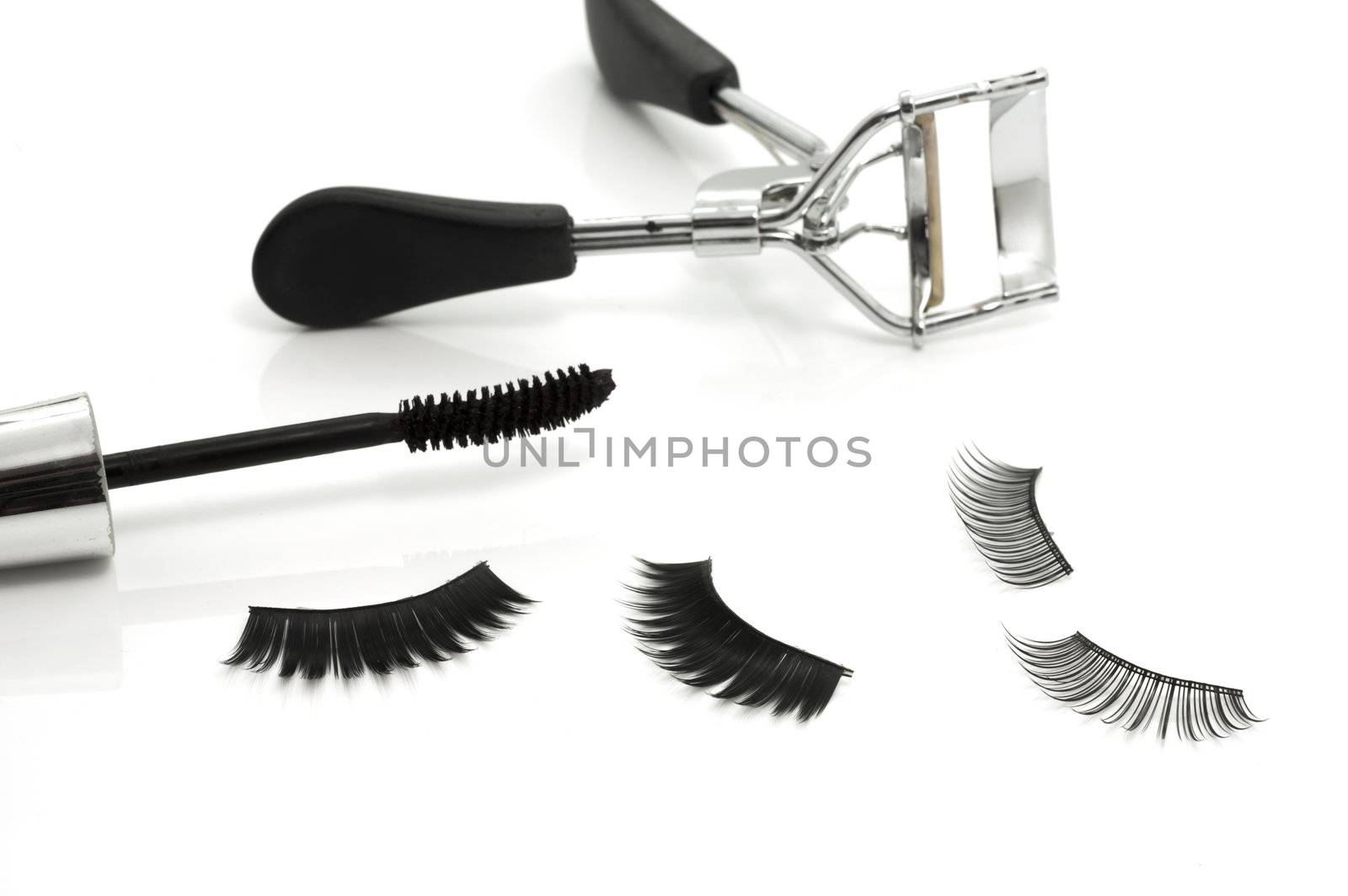 Macro of eyelash curler, mascara and false eyelashes isolated on white