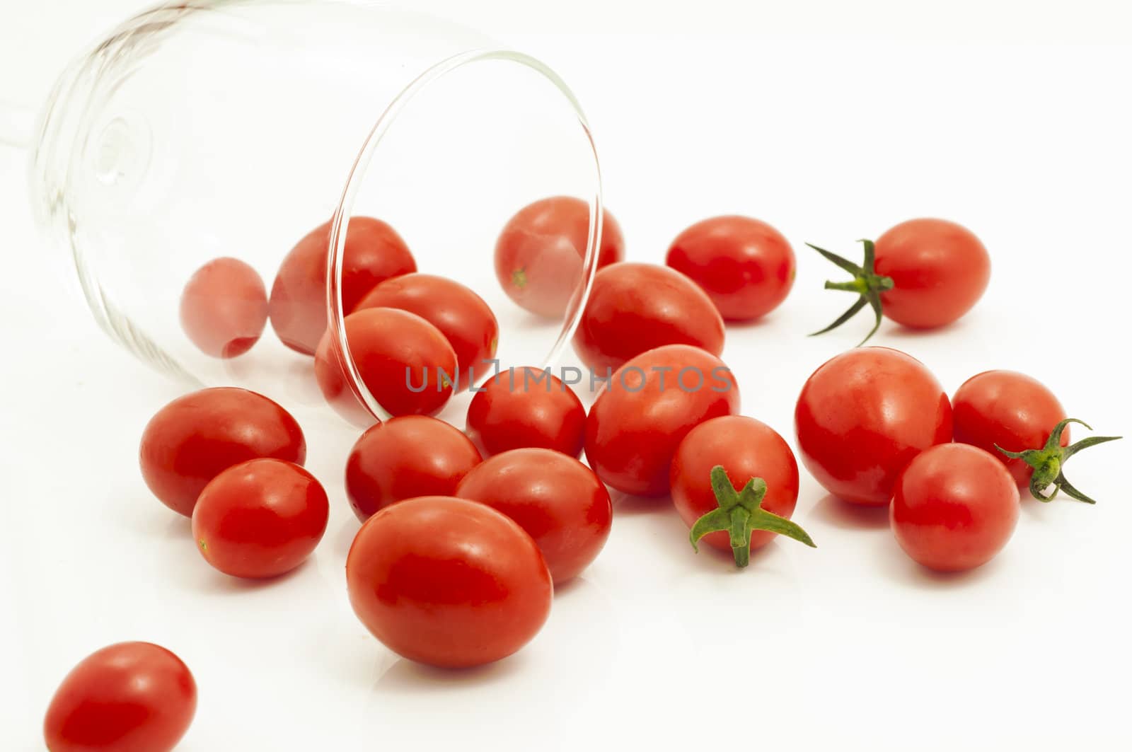 Cherry tomatoes was poured from glass. Isolated on white background