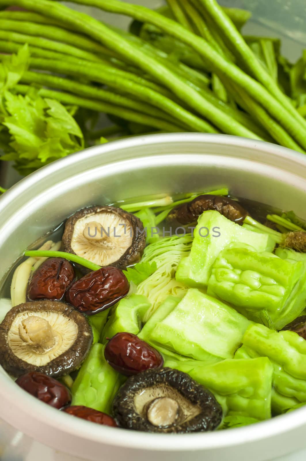 Fresh vegetable soup in a pot with mixed vegetables around it