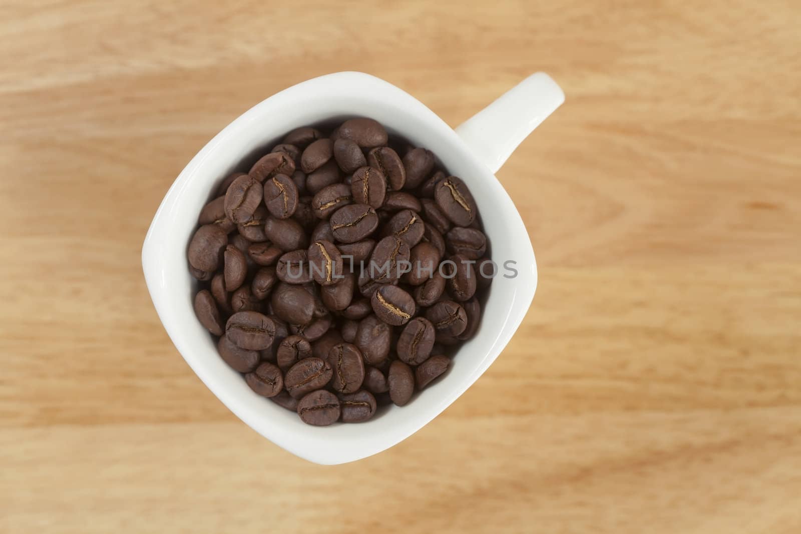 Coffee beans in a cup on wooden background