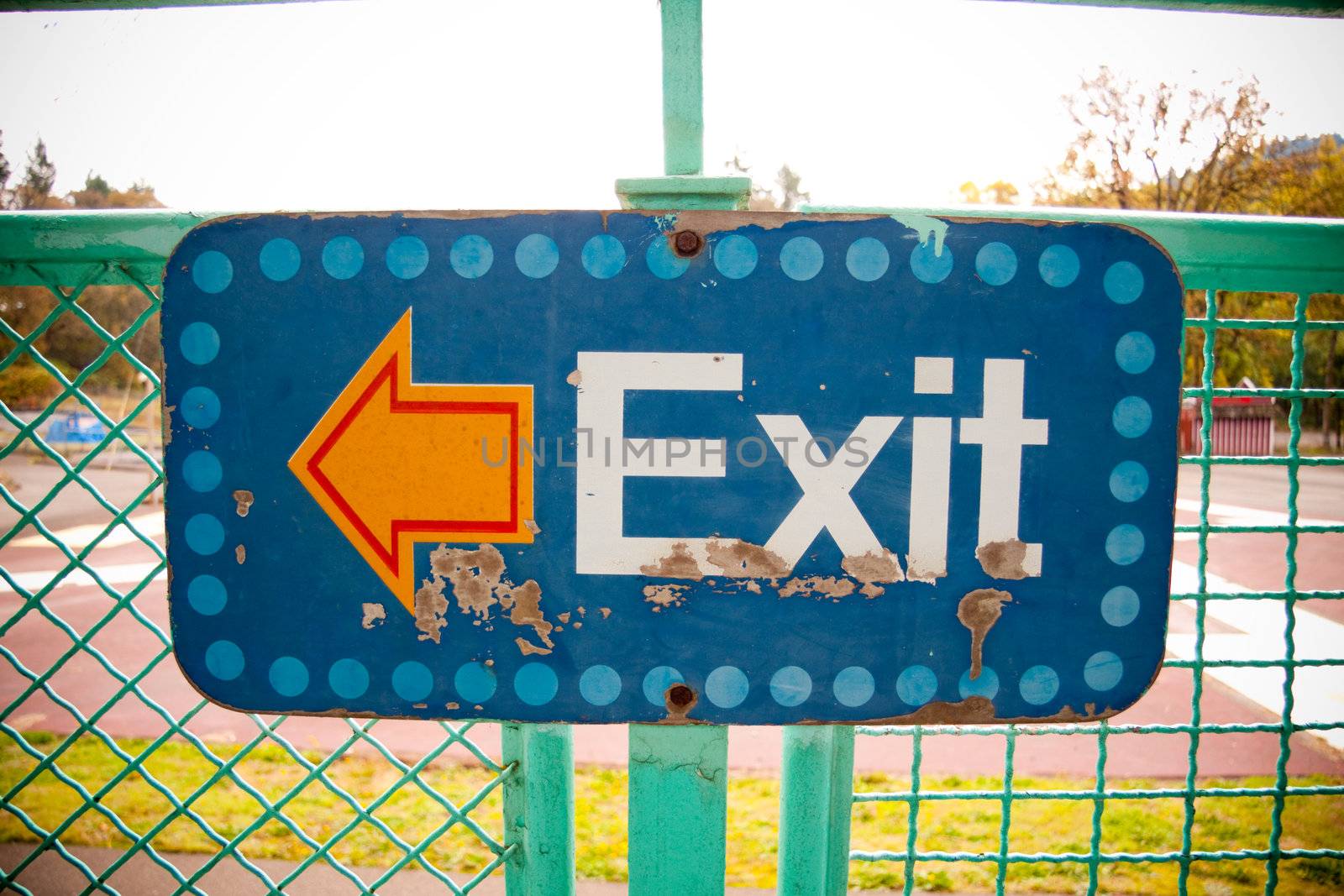 An arrow on a sign that says exit points to the left in an artsy photograph that is unique and interesting.