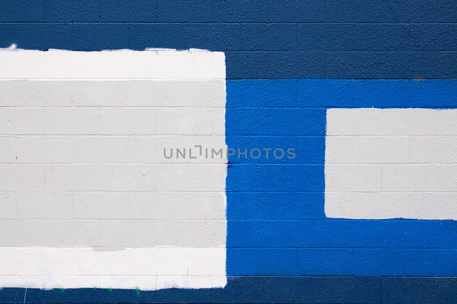 A dark blue wall with patches of grey and white to cover up graffiti in an urban scene.
