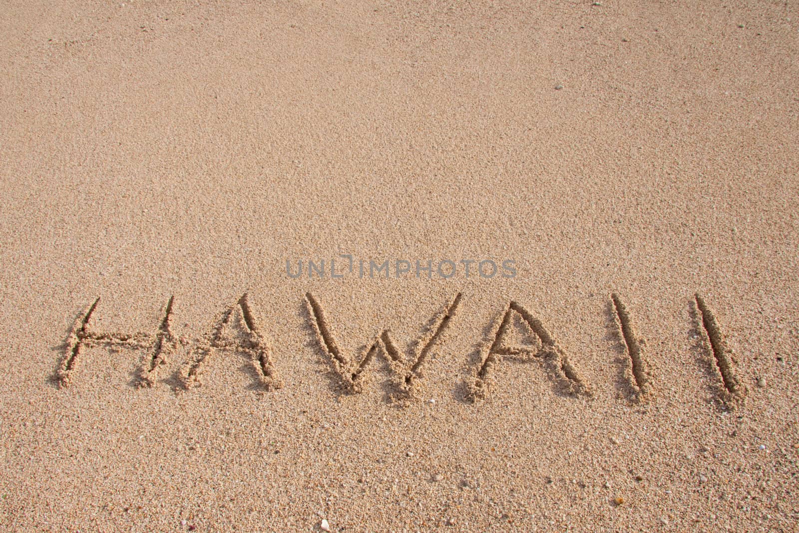 The word HAWAII is written on the beach with room for text or copy space.
