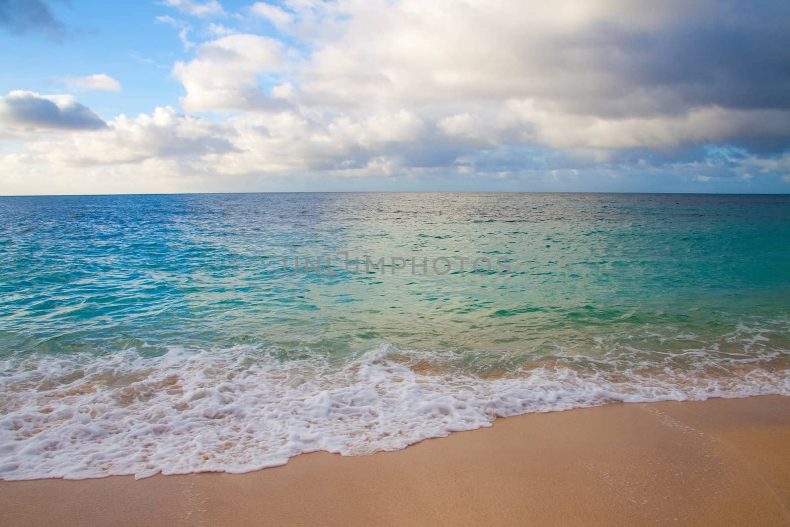 A beautiful beach with nobody in the scene as well as a dynamic sky and nice turquoise and blue tones throughout in color.