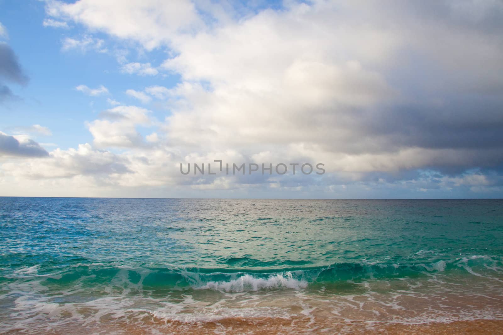 A beautiful beach with nobody in the scene as well as a dynamic sky and nice turquoise and blue tones throughout in color.