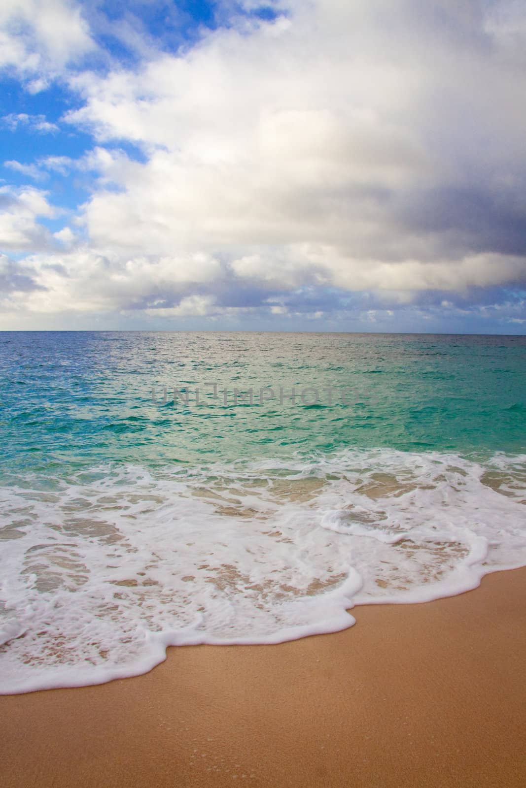 A beautiful beach with nobody in the scene as well as a dynamic sky and nice turquoise and blue tones throughout in color.