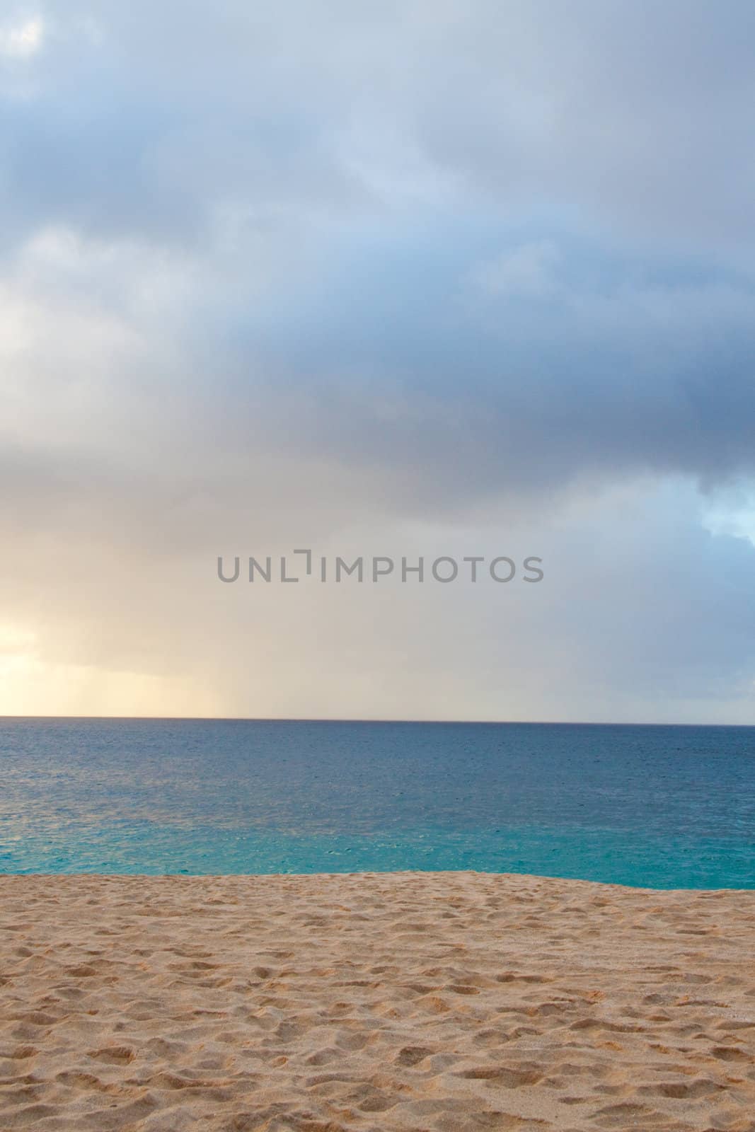 A beautiful beach with nobody in the scene as well as a dynamic sky and nice turquoise and blue tones throughout in color.
