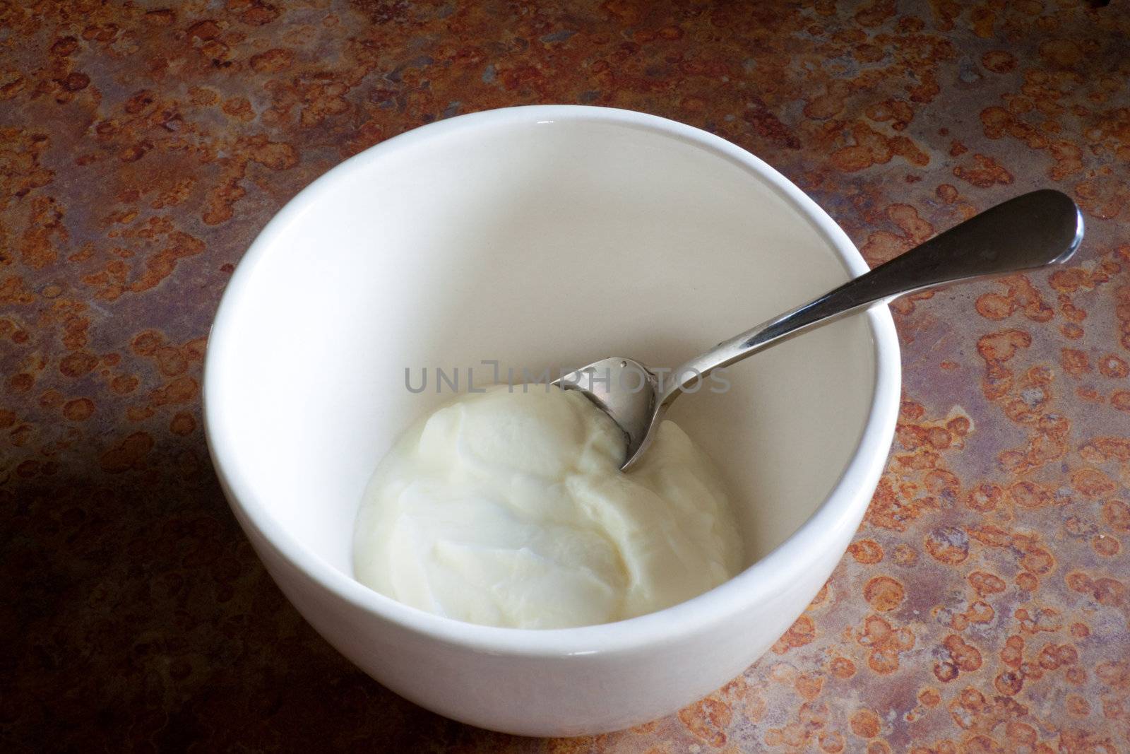 Plain white yogurt sits in a large bowl waiting for toppings to complete this healthy nutritious breakfast meal.