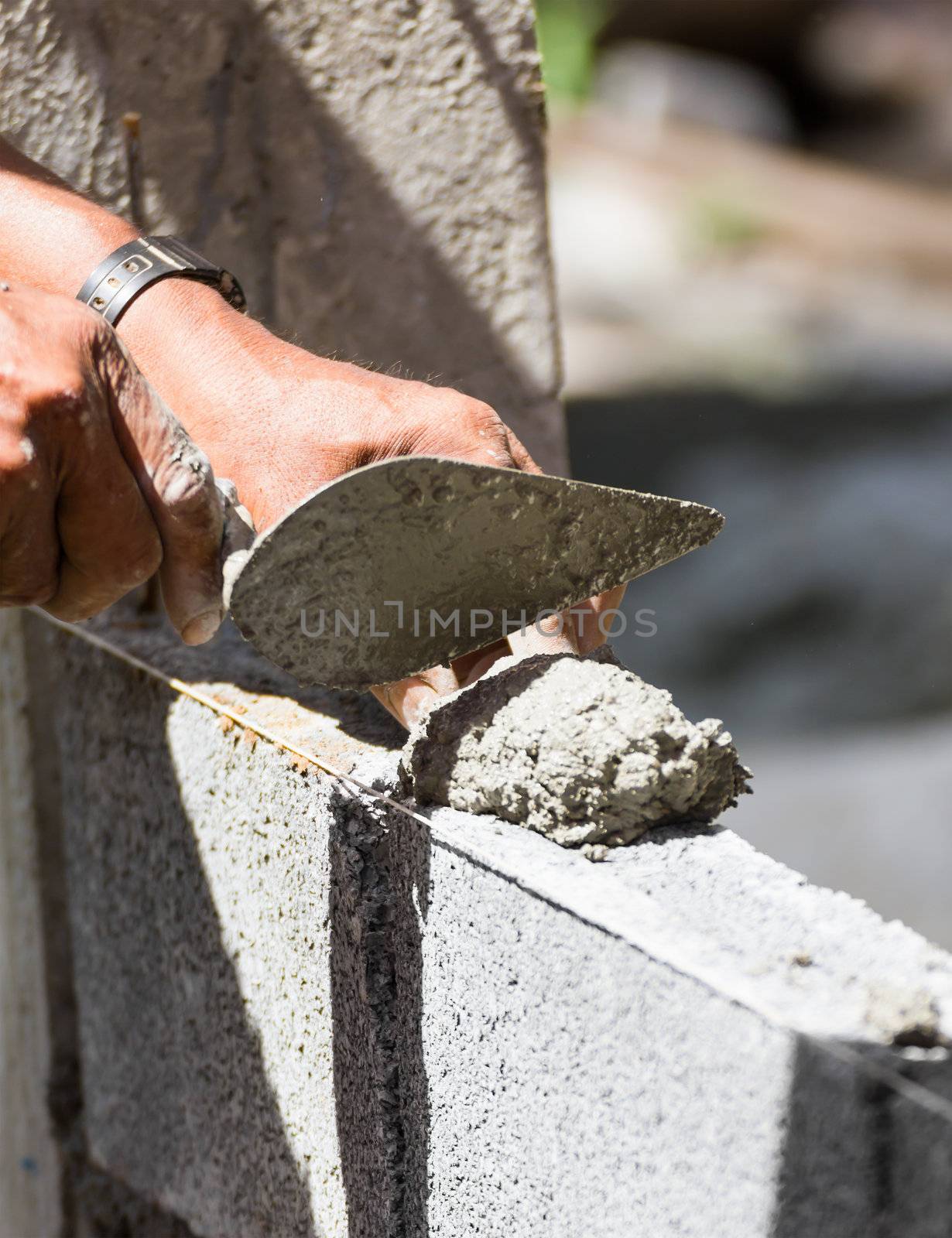 Bricklayer putting down another row of bricks in site