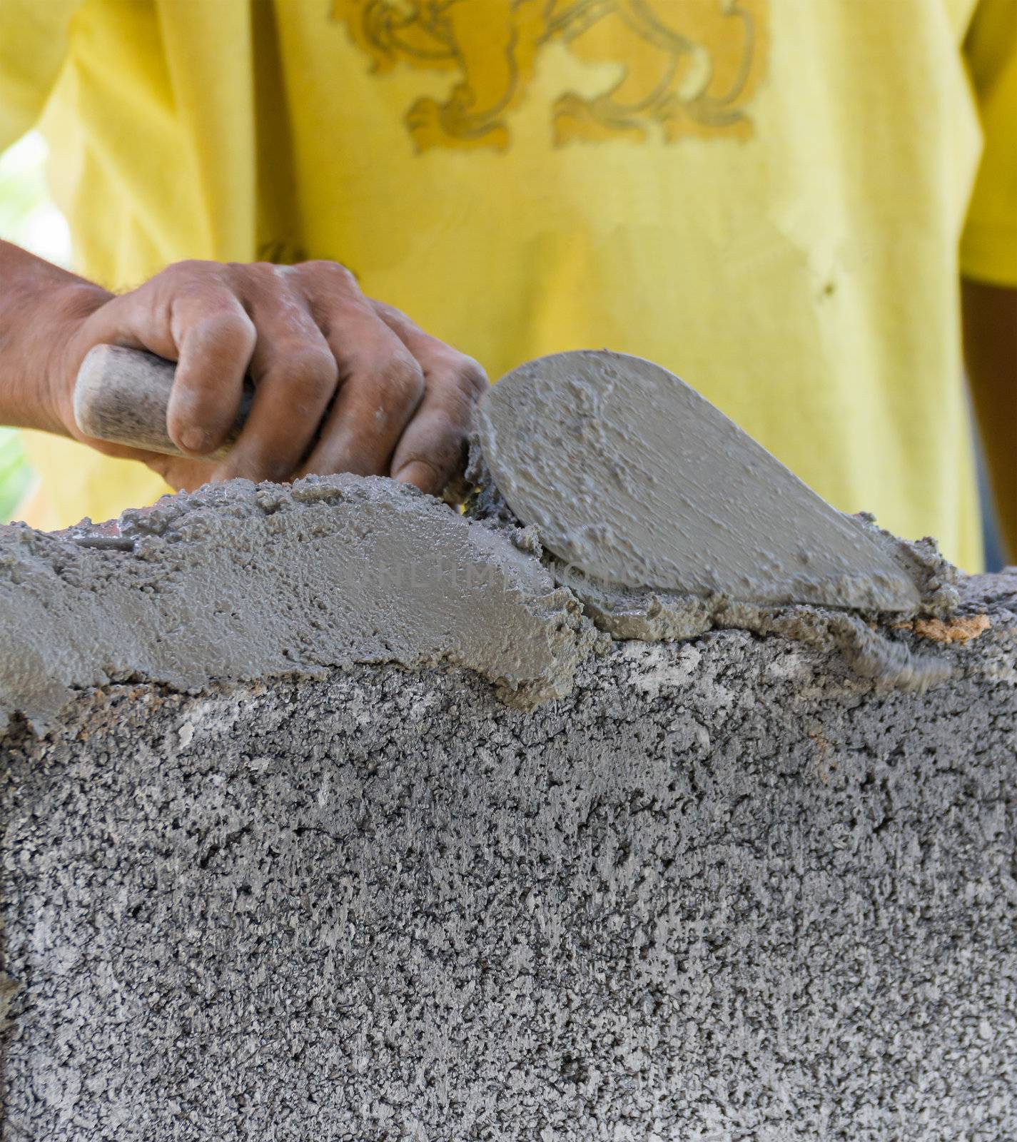 Bricklayer putting down another row of bricks in site