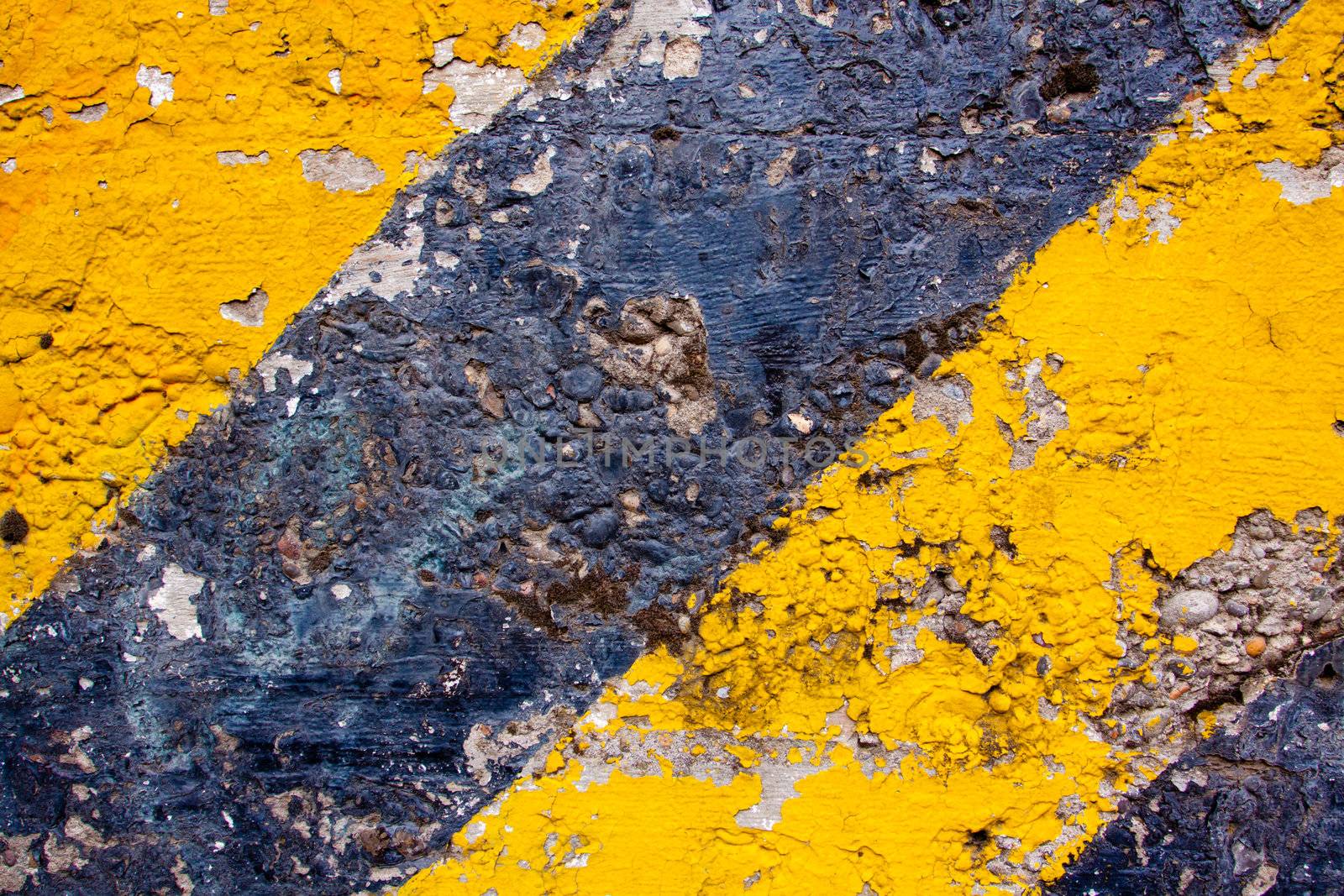 A black and yellow old wall is striped for warning or caution to create an abstract texture of a rubble decaying building wall.