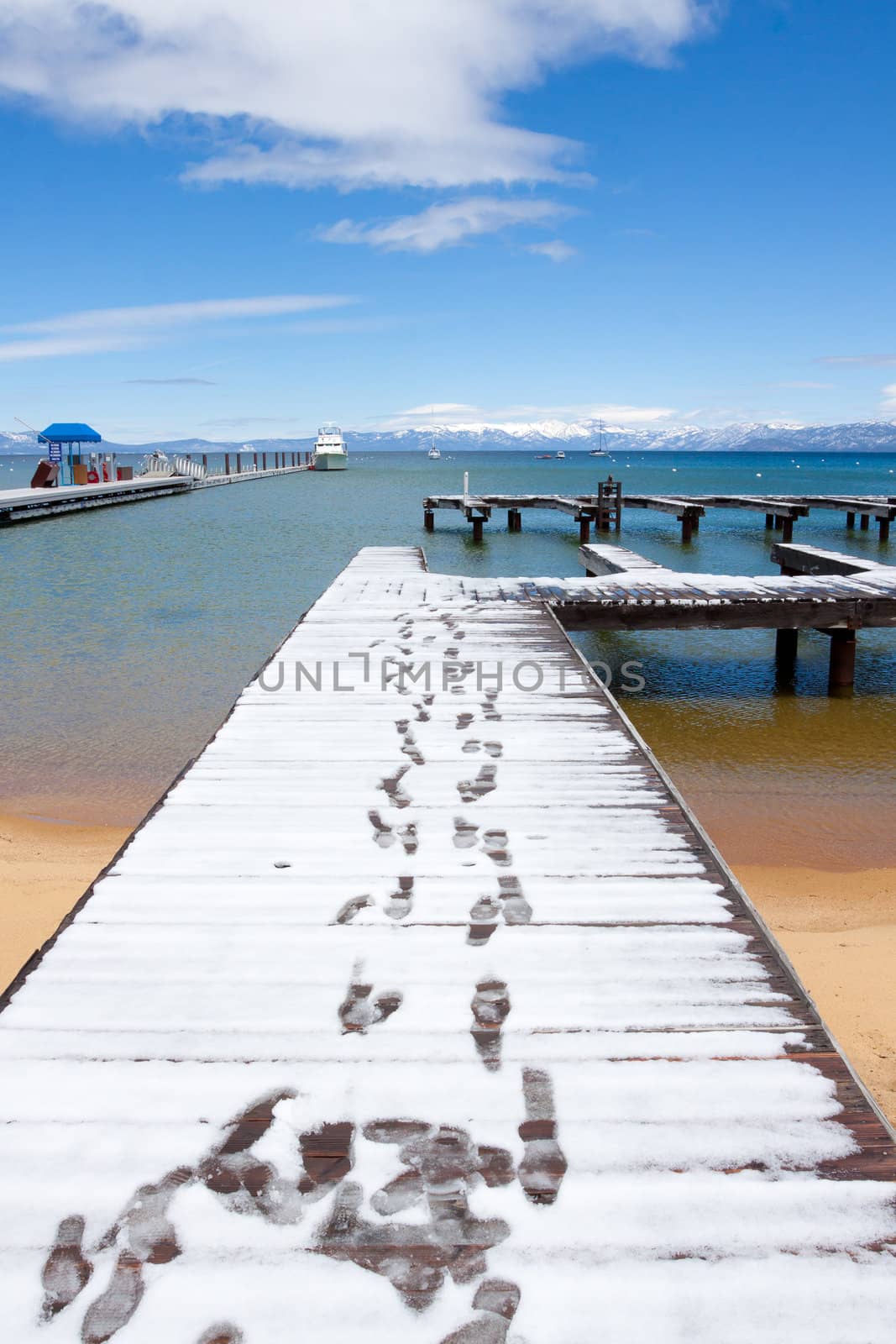 Views of Lake Tahoe in California with crystal clear water, snow on the ground, and mountains in the background.