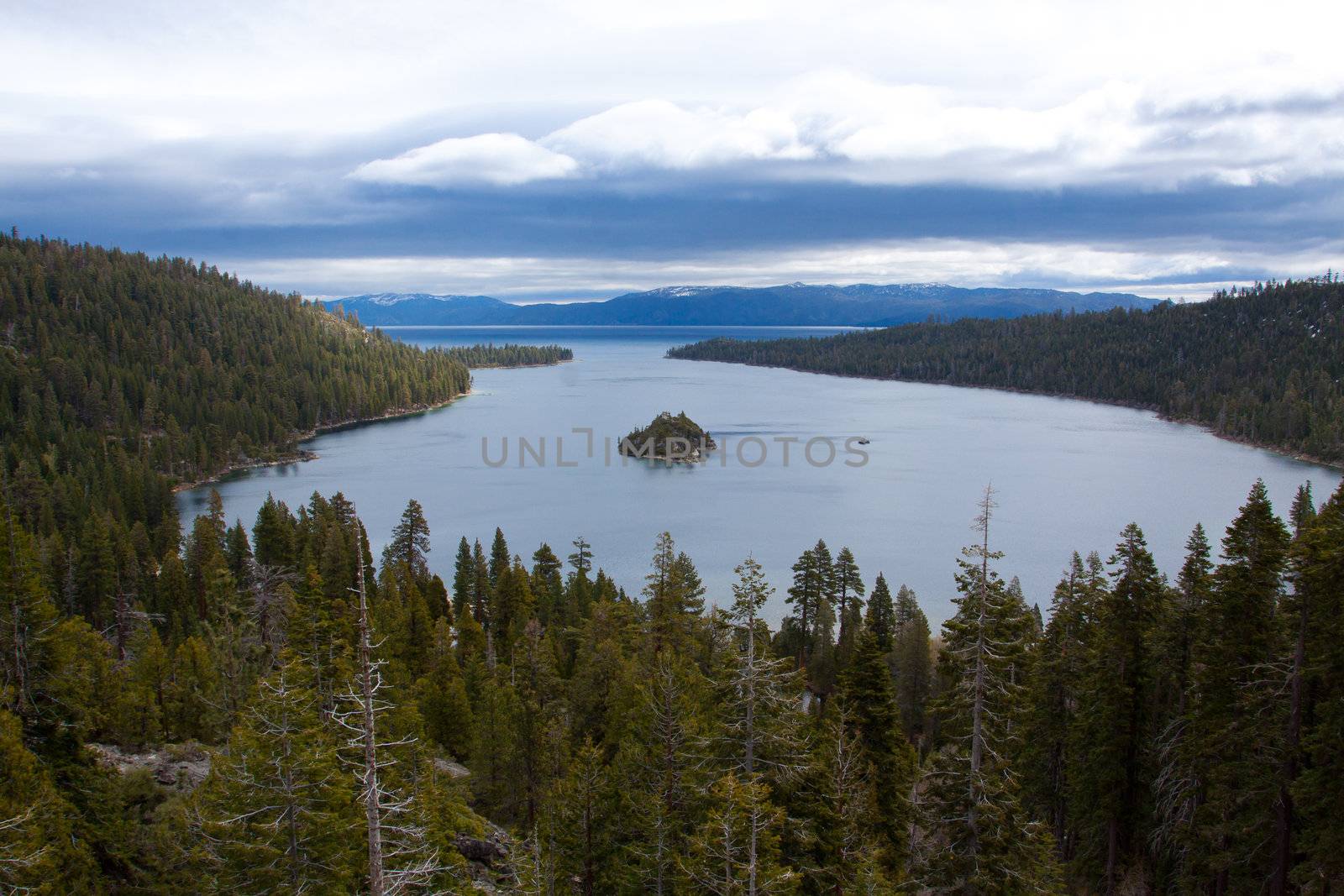 Views of Lake Tahoe in California with crystal clear water, snow on the ground, and mountains in the background.