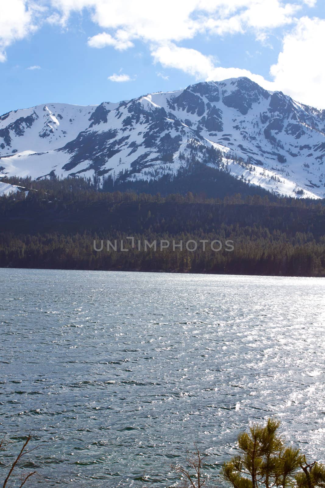 Views of Lake Tahoe in California with crystal clear water, snow on the ground, and mountains in the background.