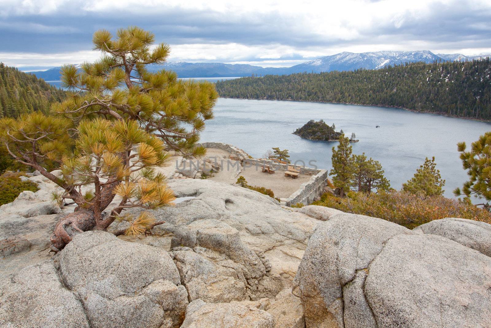 Views of Lake Tahoe in California with crystal clear water, snow on the ground, and mountains in the background.