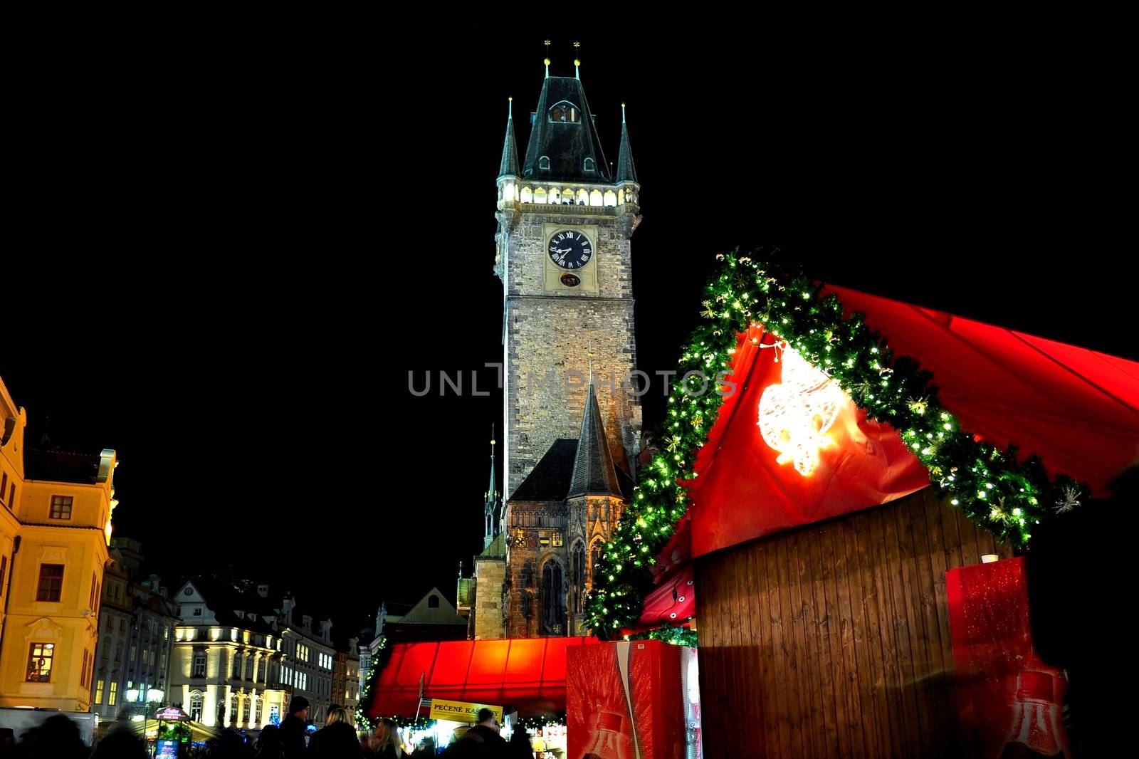 Christmas & New Year Eve illumination and atmosphere on Old Town Square in Prague, with Prague Astronomical Clock on the background, with christmas market stand, by night