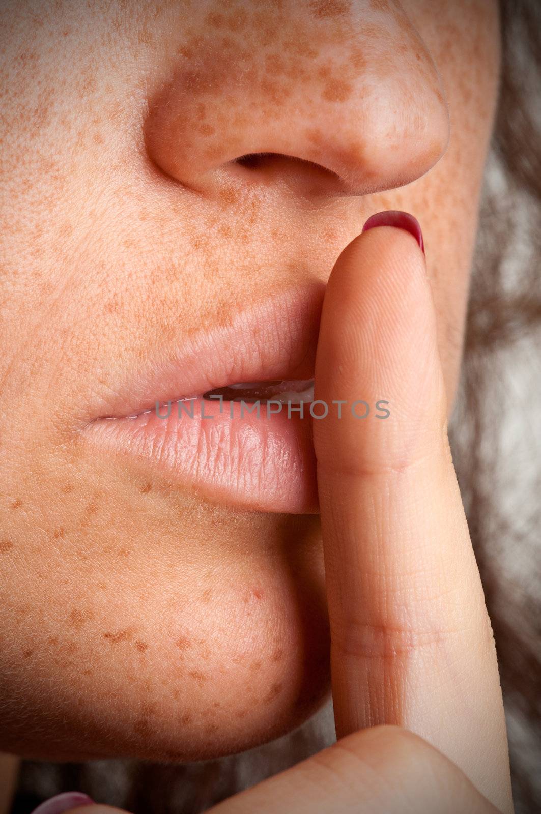 Closeup of a woman with her finger over her mouth