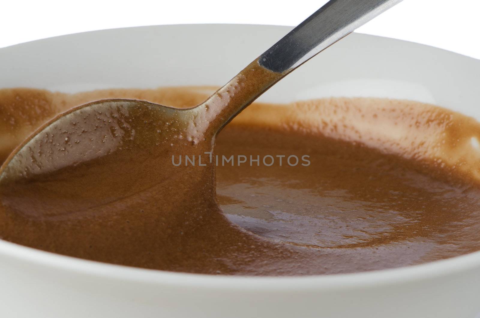Chocolate mousse on a white mug with spoon on white background.