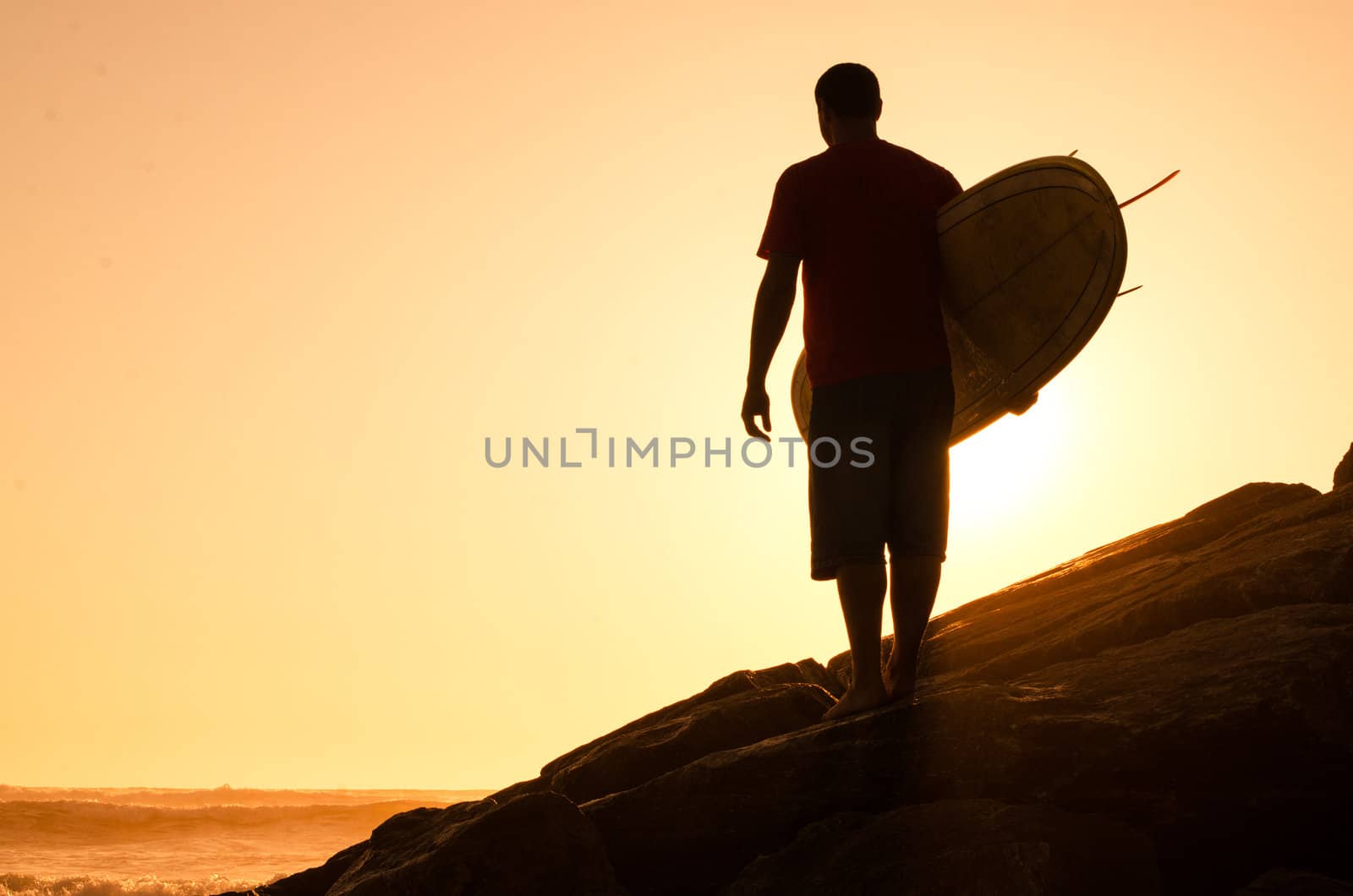 A surfer watching the waves at sunset in Portugal.