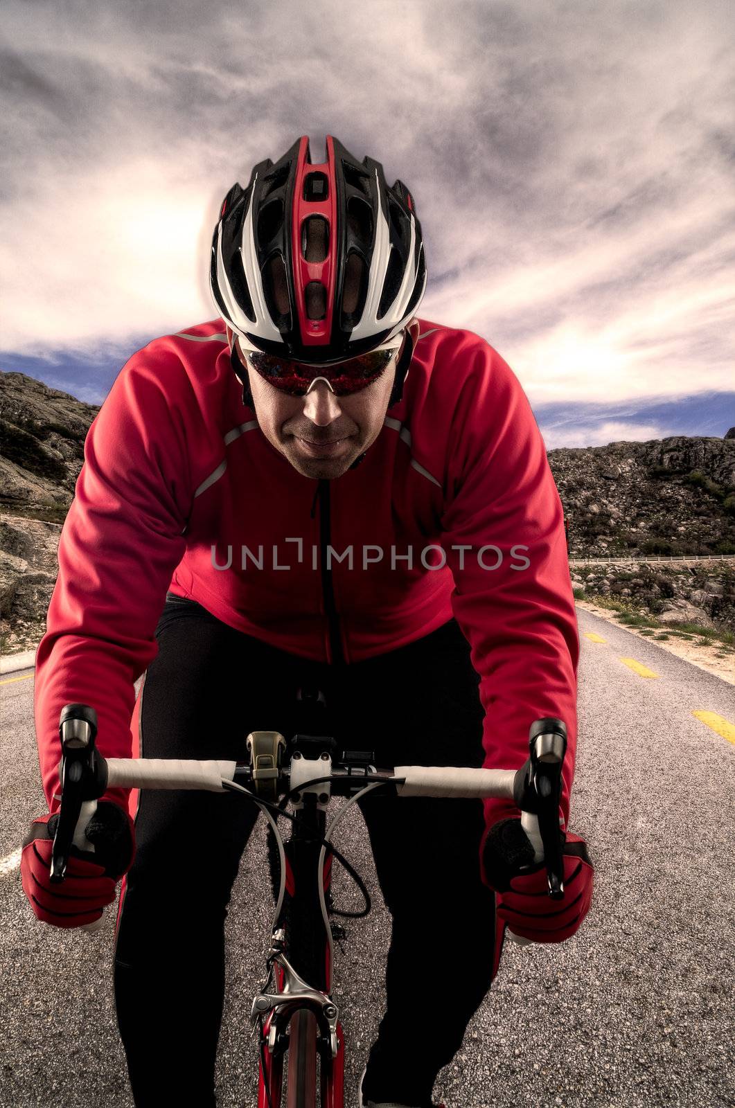 Cyclist on road bike through a asphalt road in the mountains and blue sky with clouds.