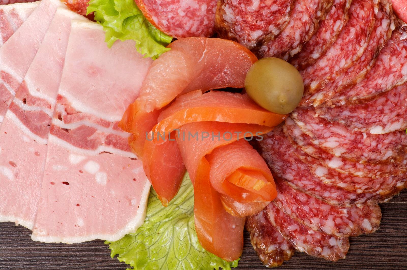 Arrangement of Cold Meats with Salami, Smoked Pork, Сarpaccio, Baloney, Sausage and Green Olives closeup