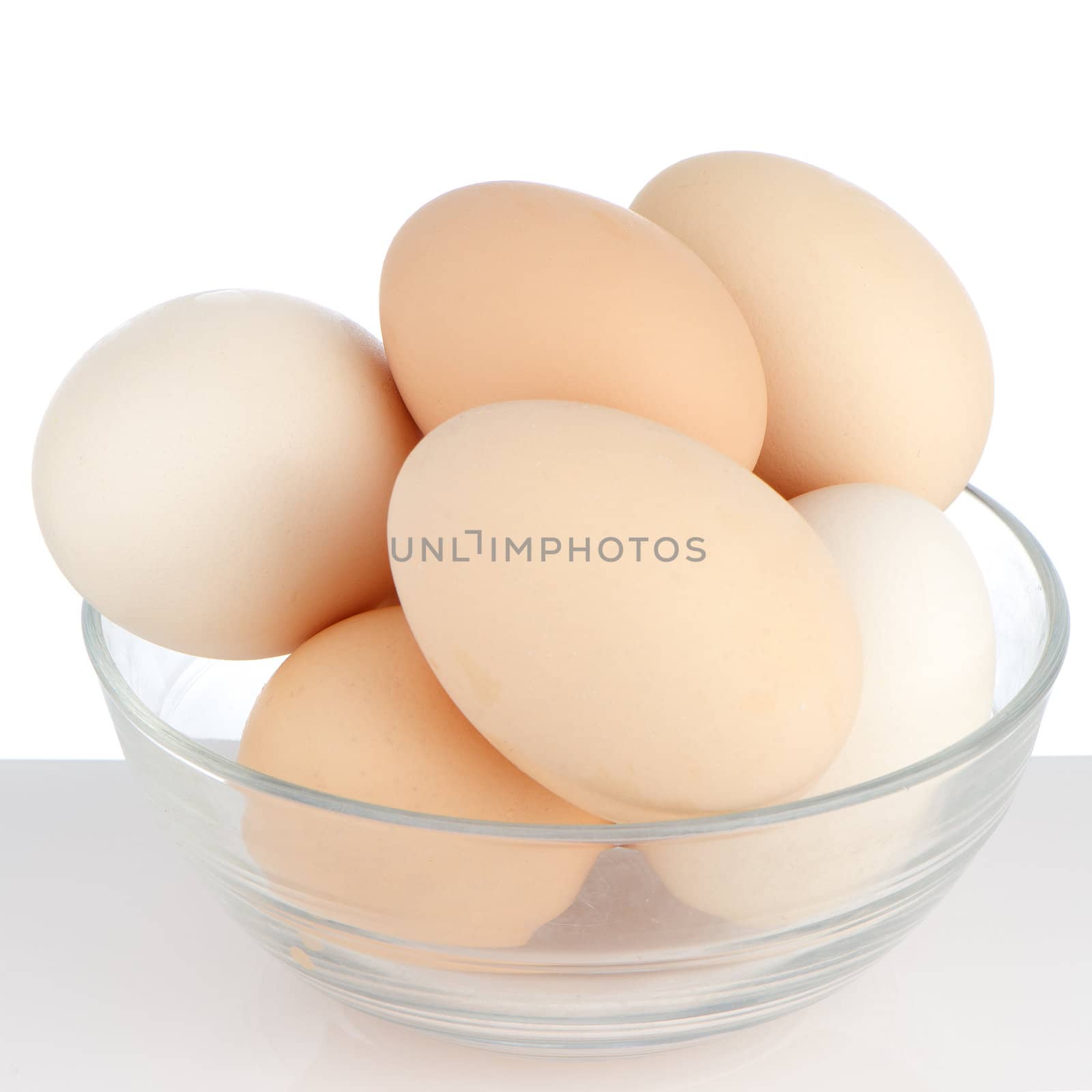 Brown eggs in transparent bowl on white background.
