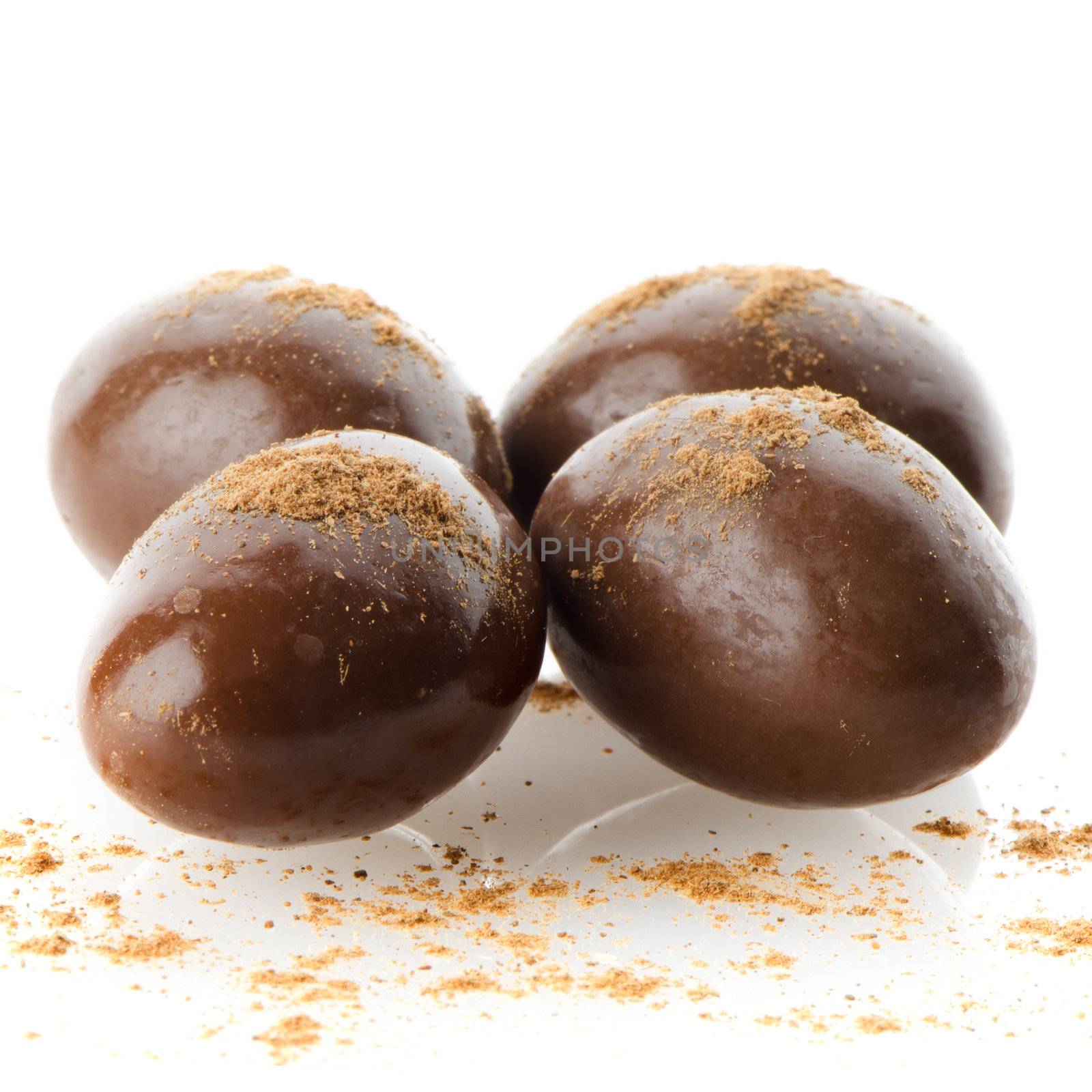 Chocolate candies on white reflective background.