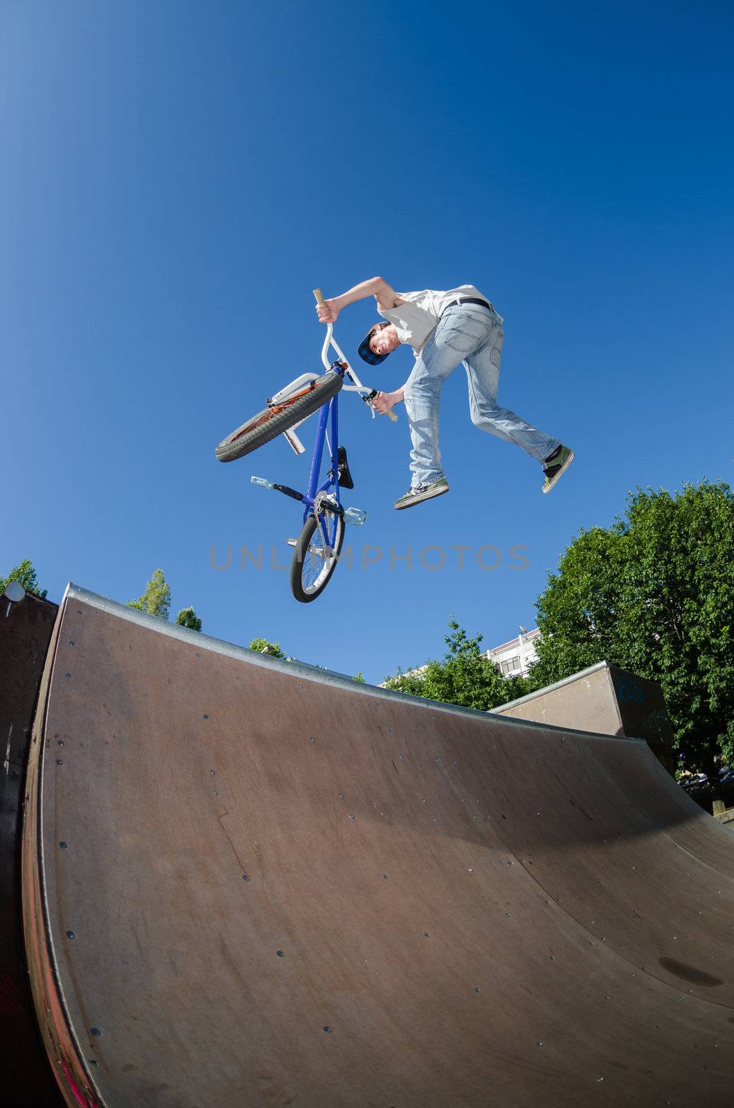 Bmx rider performing a tail whip at a quarter pipe ramp on a skatepark.