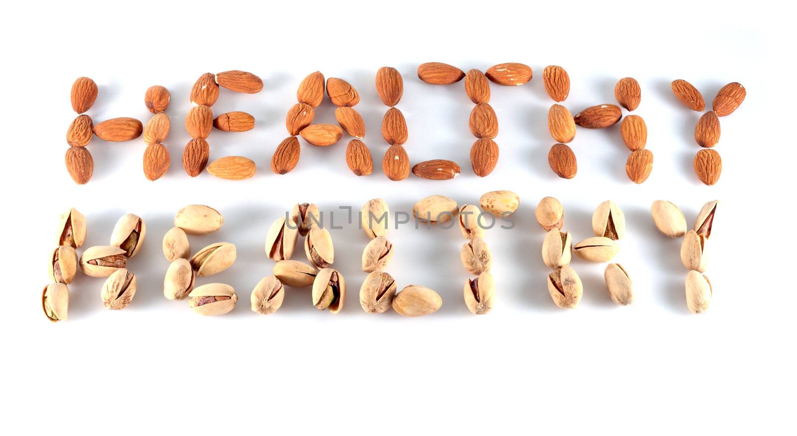 almonds and pistachios composing the word healthy on white background