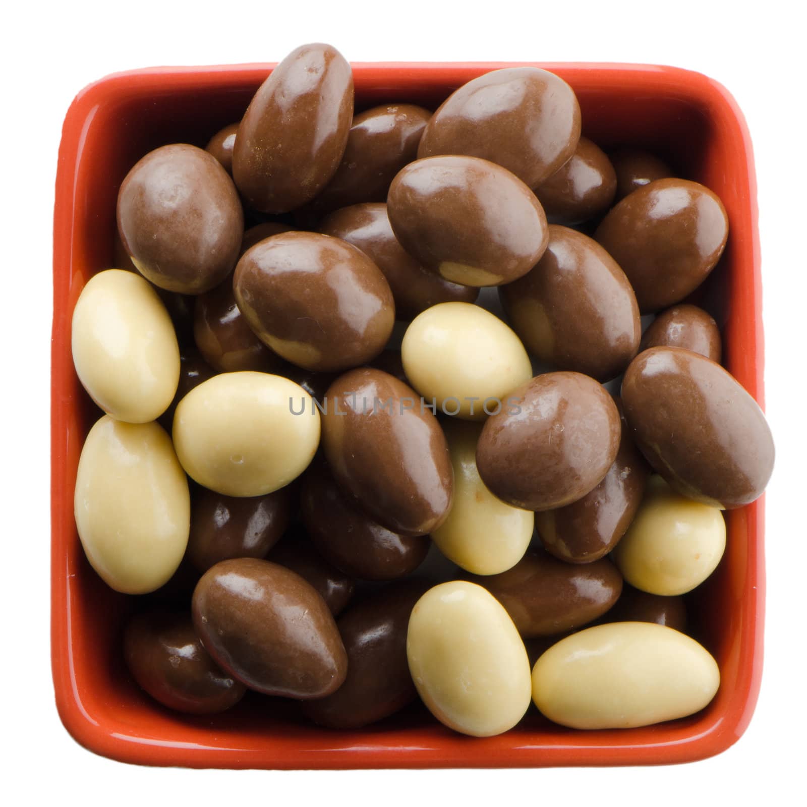 Red bowl with chocolates on white background.
