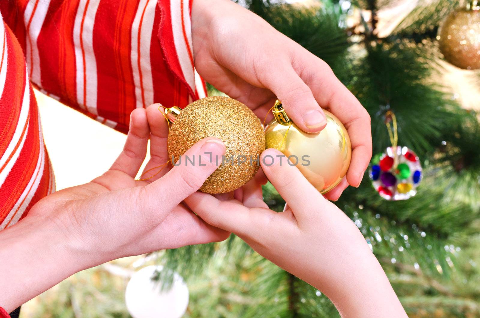 Hands of sister and brother with gold baubles - Sister handing Christmas balls to younger brother, Closeup to hands, Horizontal shot