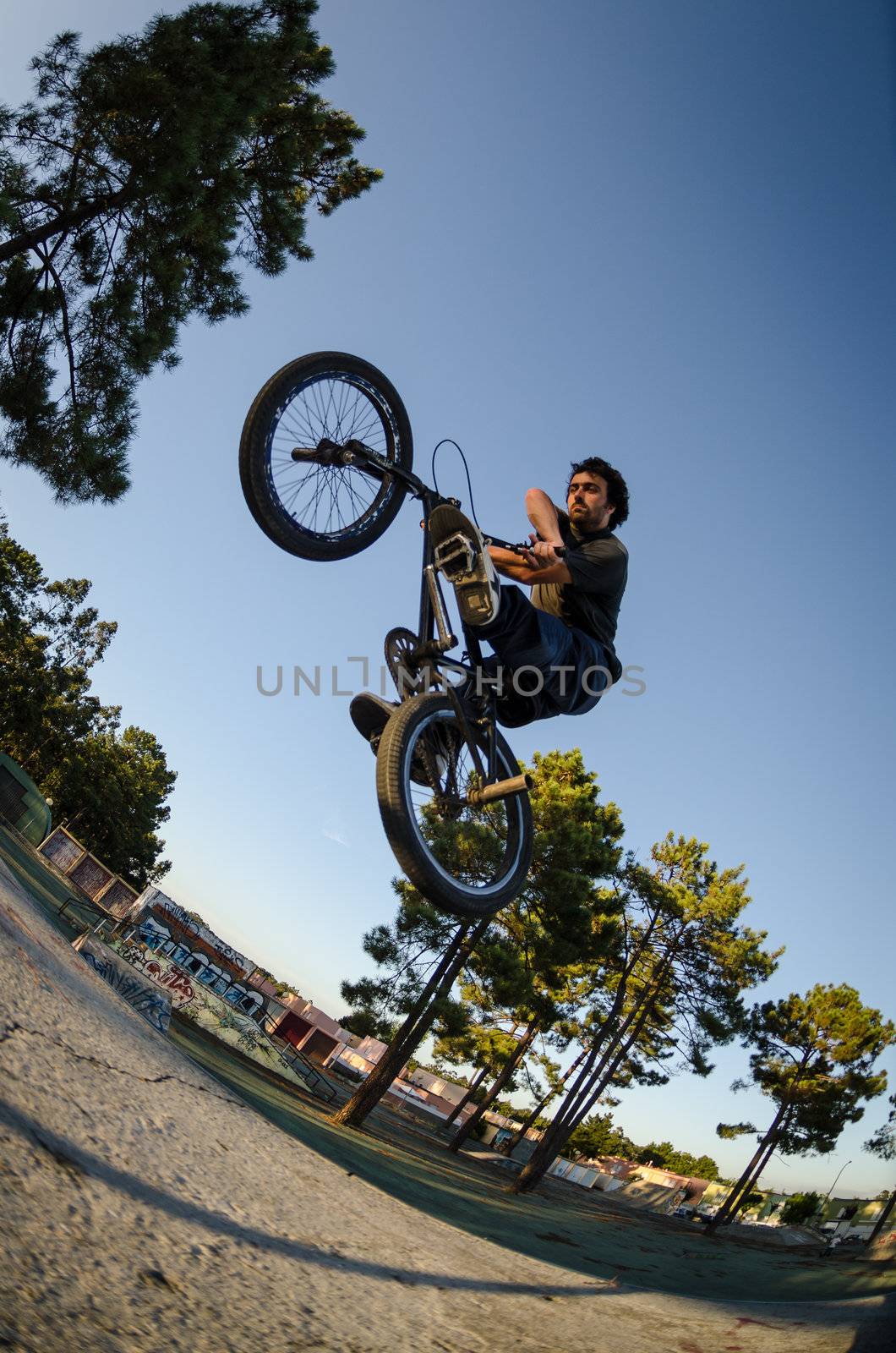 BMX rider jumps while doing cross bar trick.