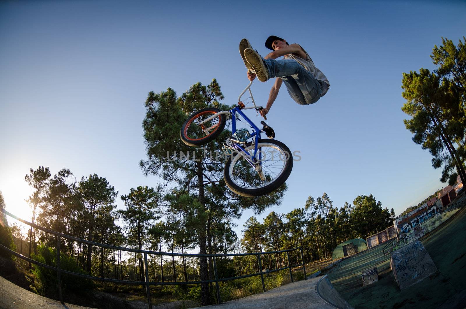 Bmx rider performing a can-can at a quarter pipe ramp on a skatepark.