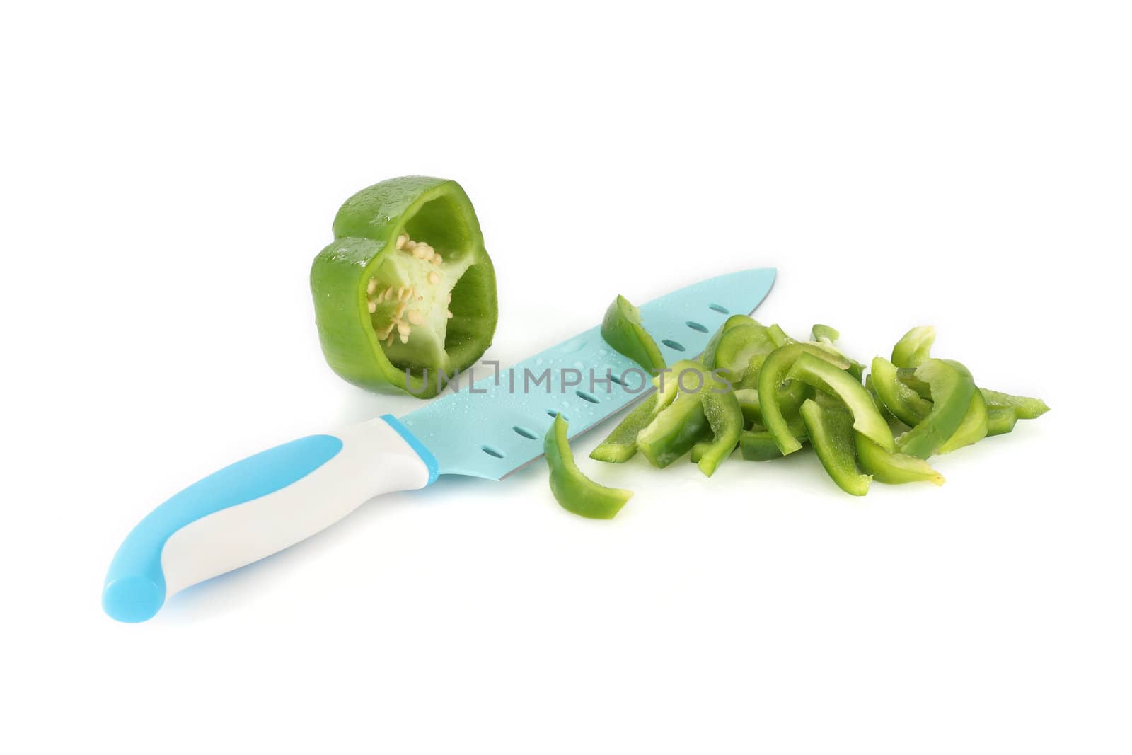 green pepper cut into strips with kitchen knife on white background
