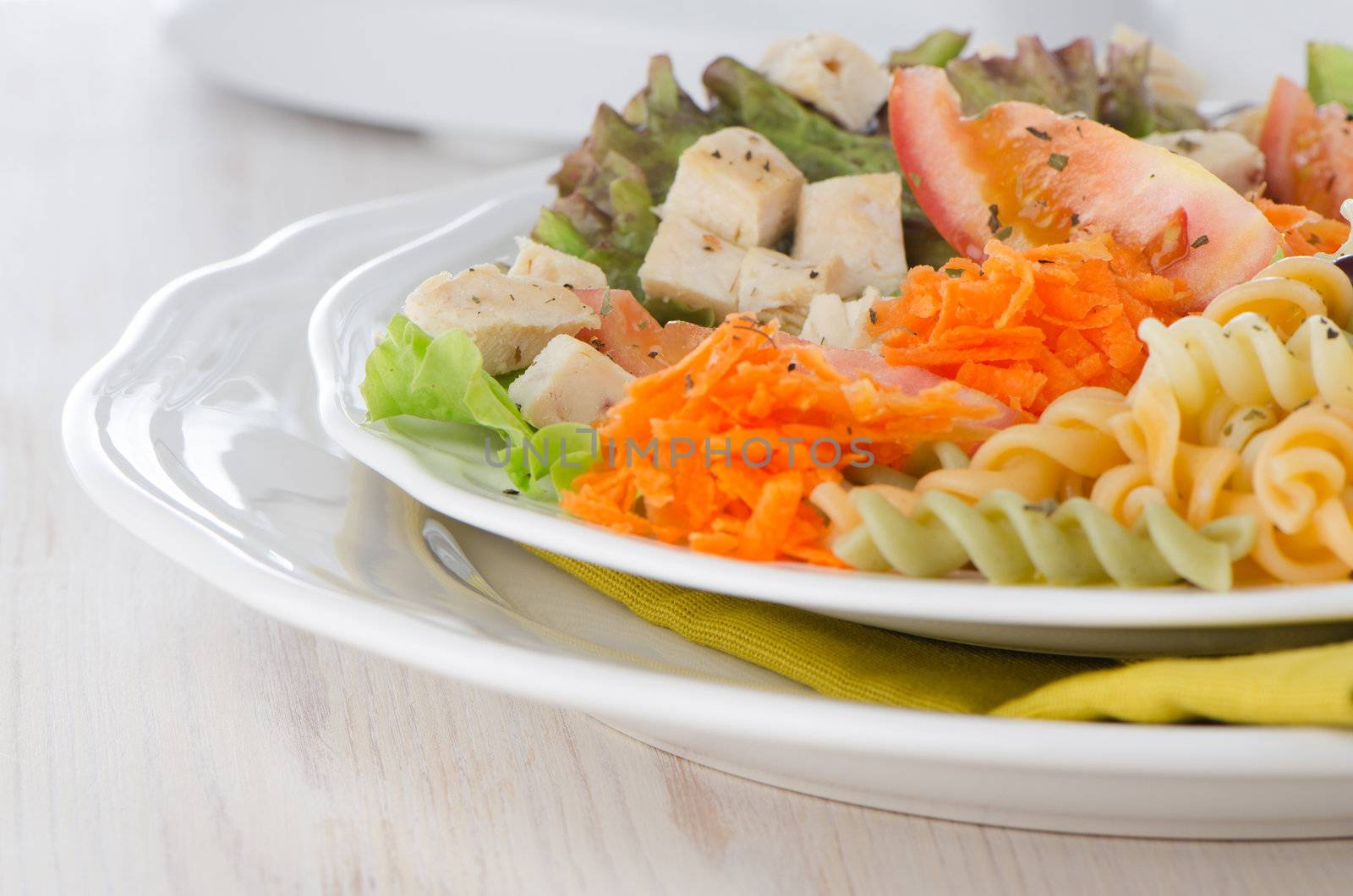 Mixed salad on a white plate and a white wood background.