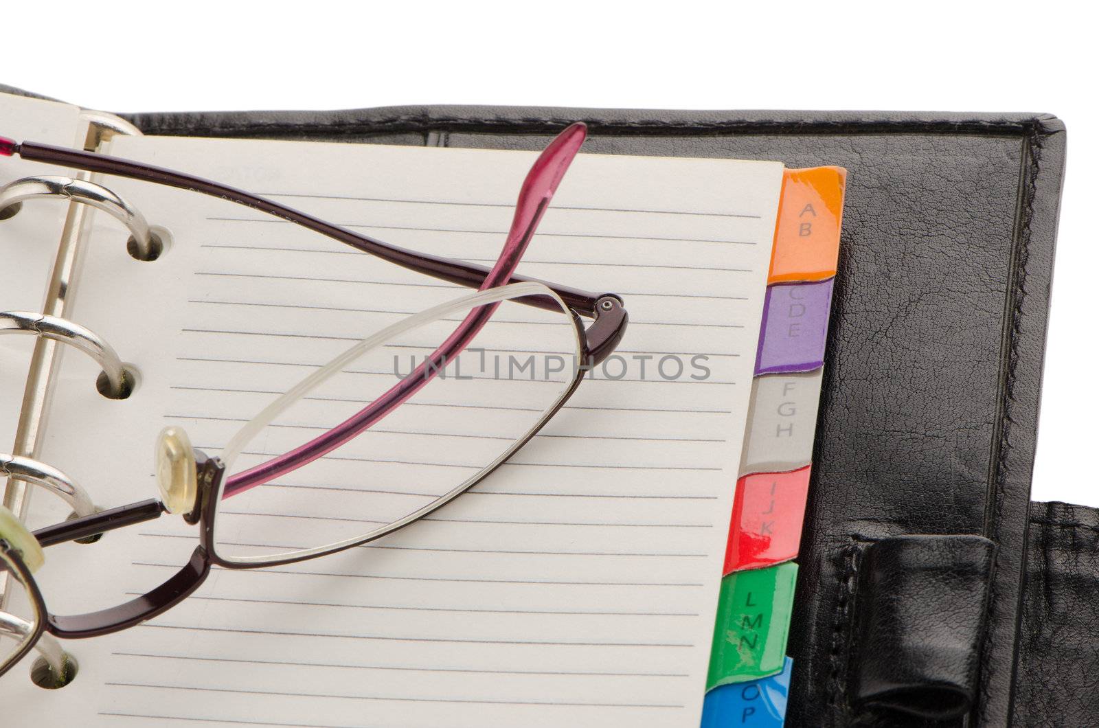 Leather notebook and glasses on white reflective background.