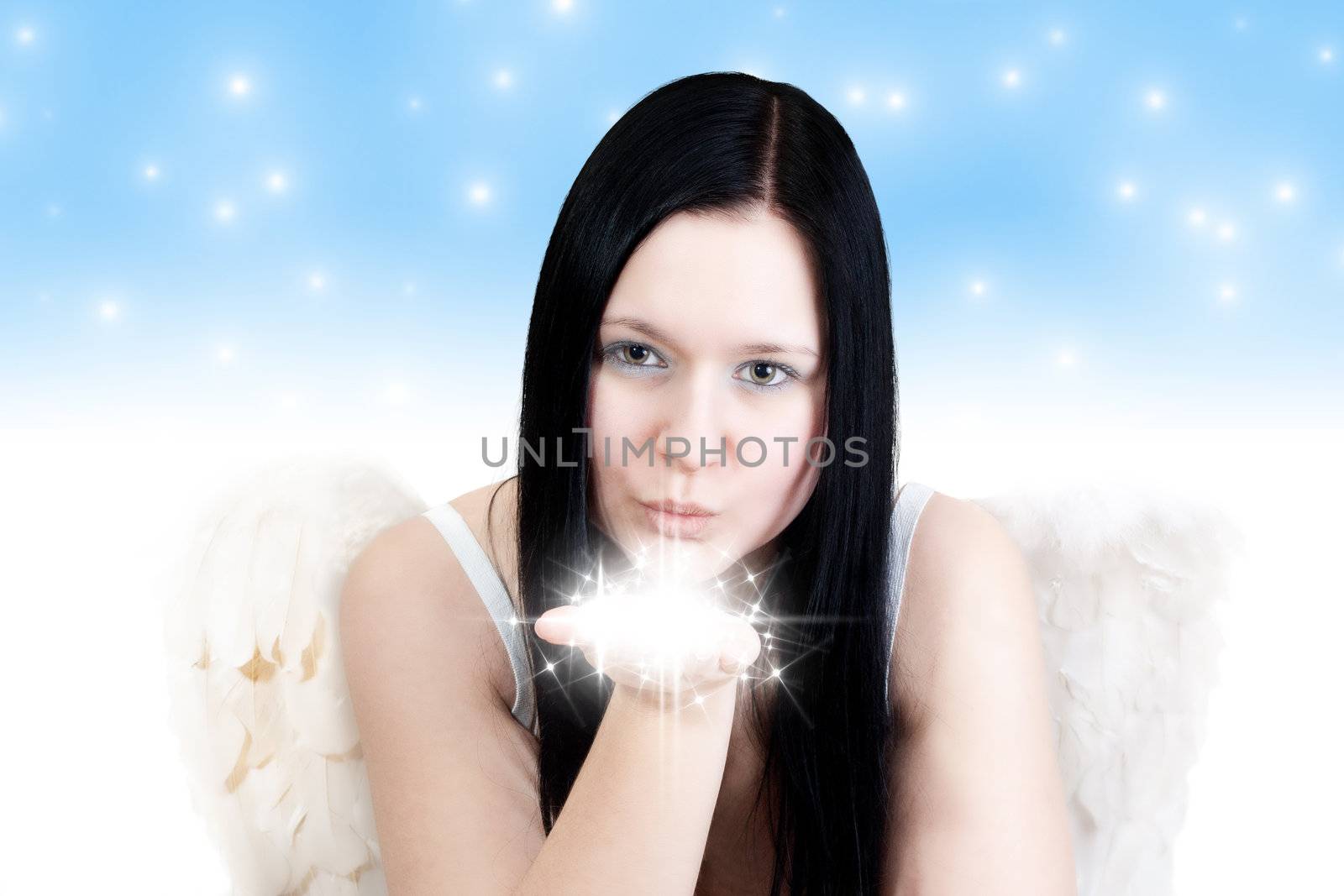 Young blackhaired woman with angel wings blowing some stars on blue background