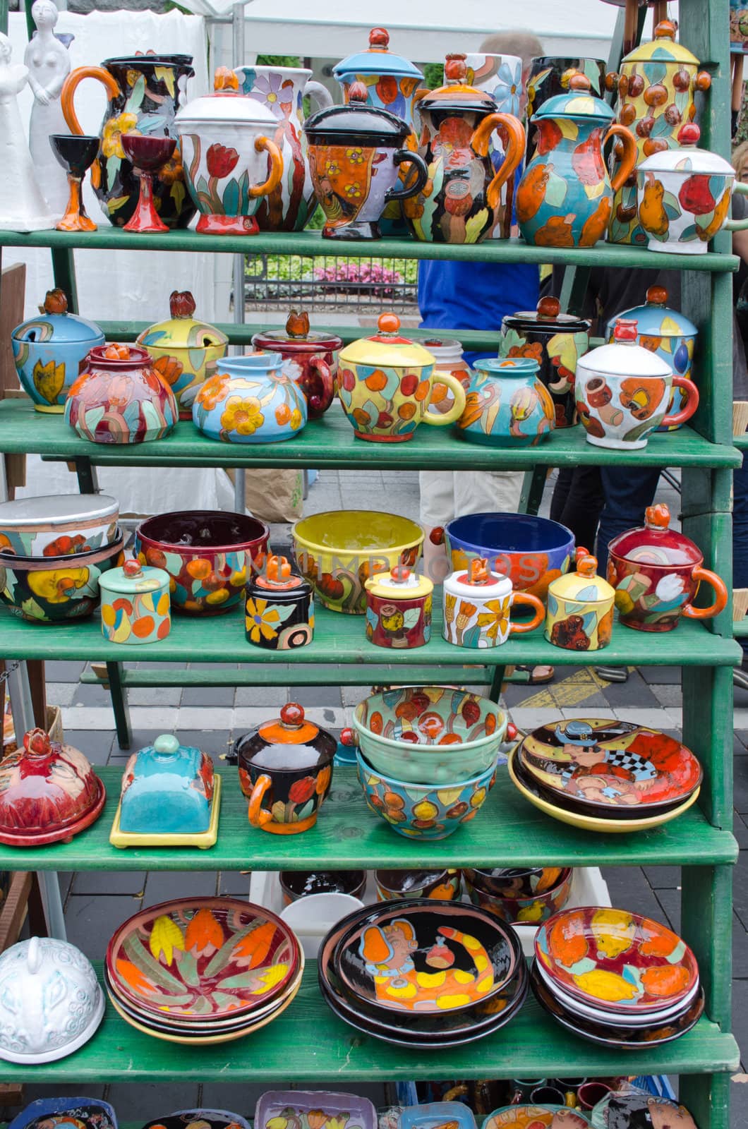 various colorful handmade clay pottery craft dishes pots cups jugs and other sell in outdoor street fair market
