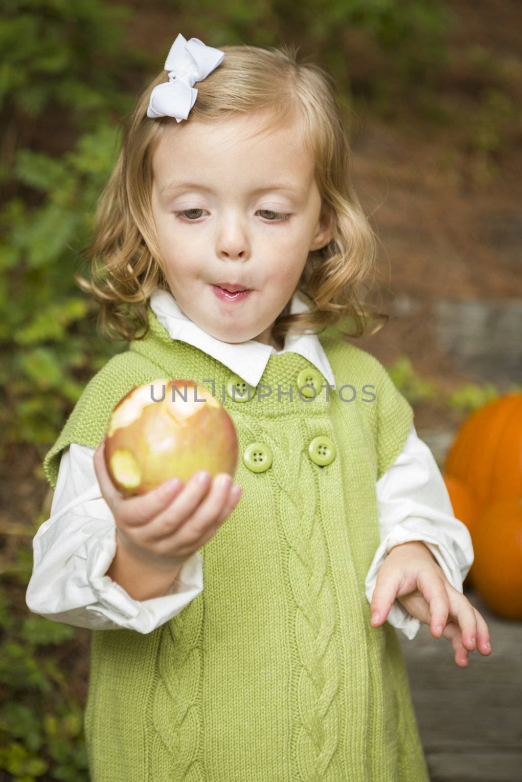 Adorable Child Gilr Eating a Delicious Red Apple Outside.