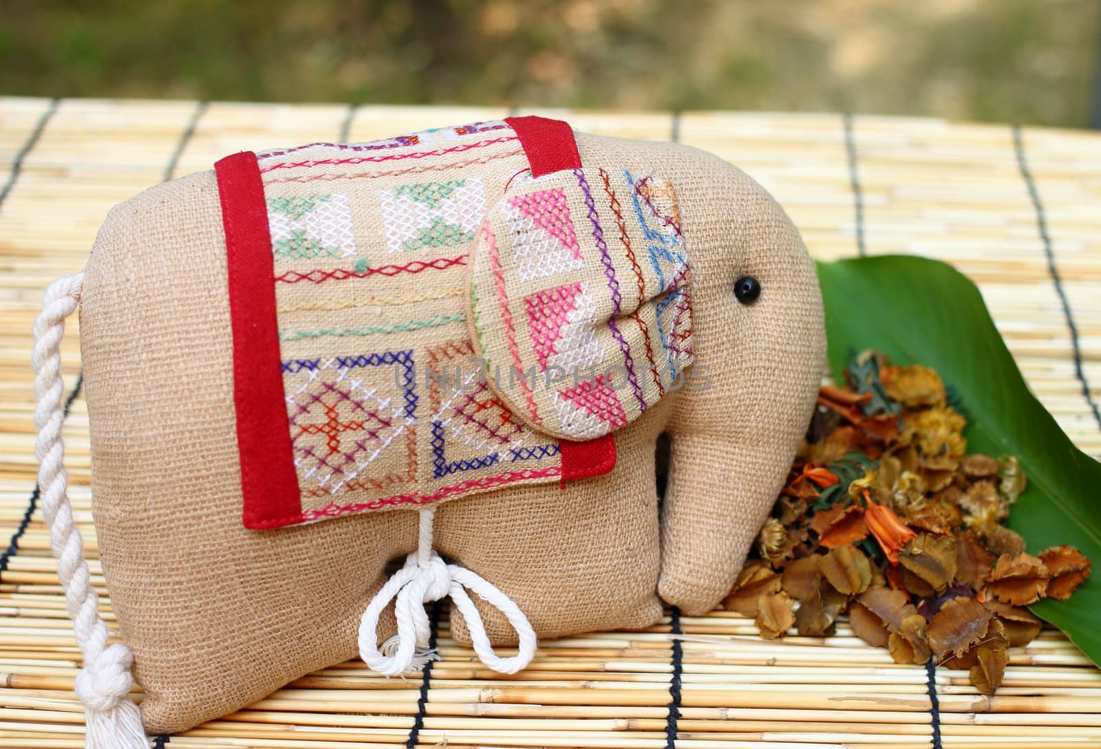 Herb package in a form of elephant with thai cloth, put on table cloth made from wooden