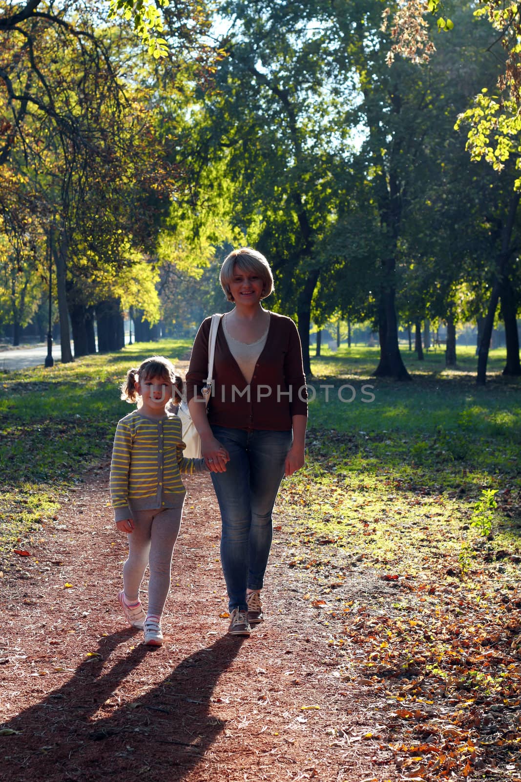 mother and daughter walking in park by goce