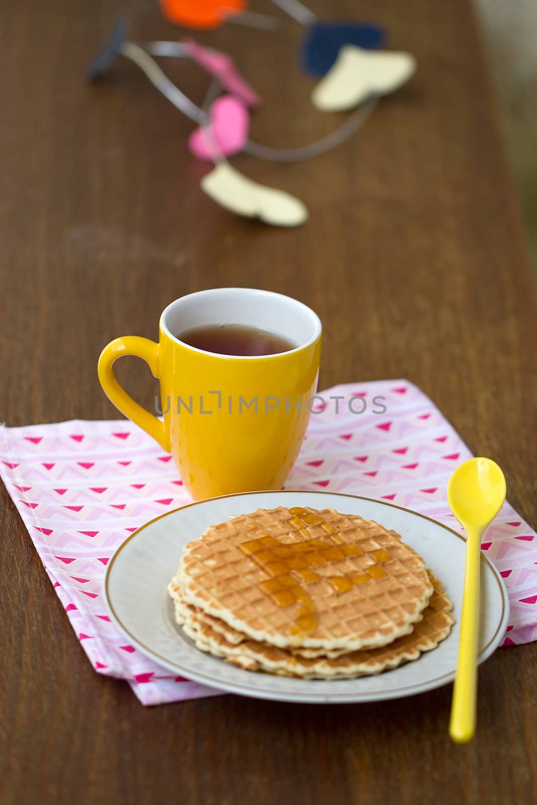 Round wafers, yellow cup with a spoon on a napkin, with a heart of paper in the background