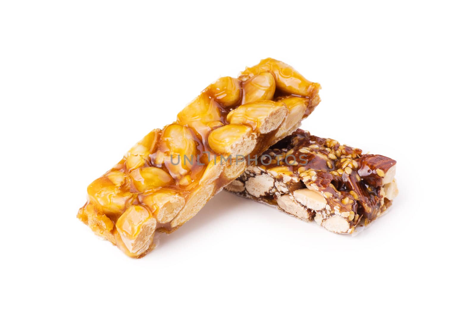 Two honey bars with peanuts and sesame seeds on white background