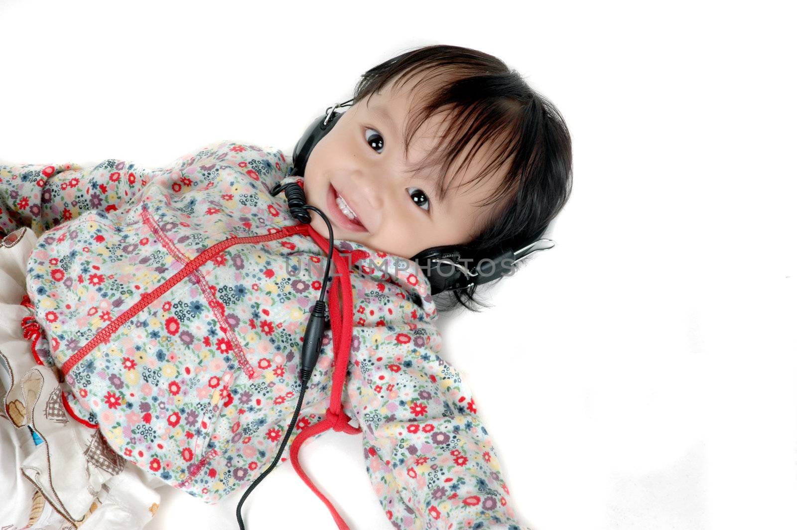 a young Asian girl lying down listening to music with headphones isolated on white background