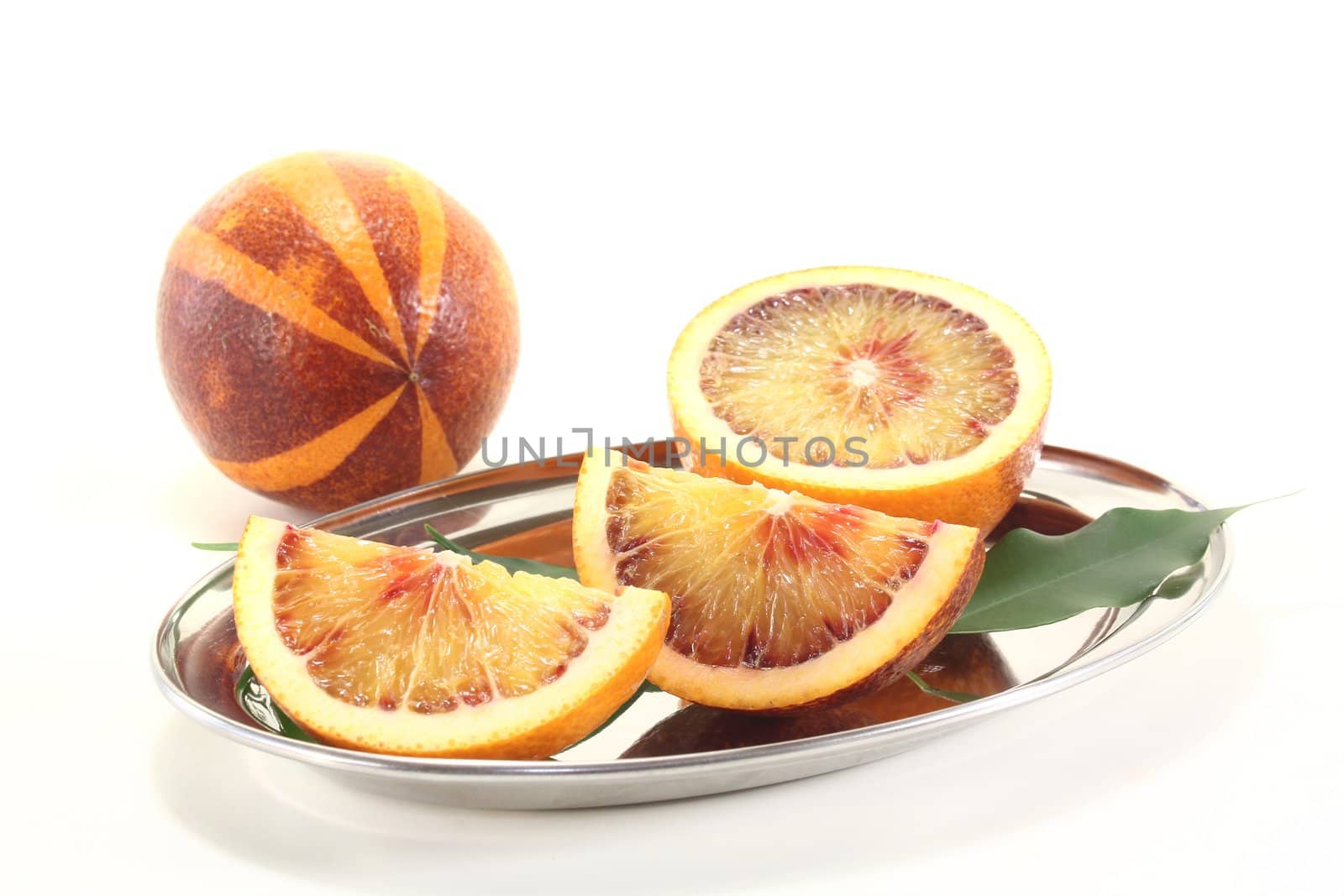 two fresh red and yellow blood oranges with leaves on a light background