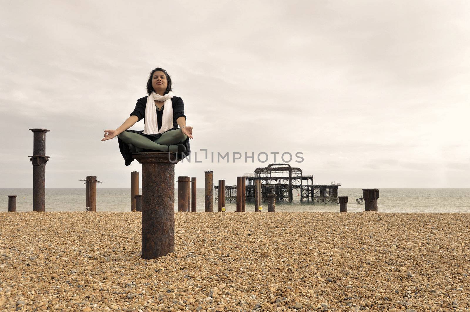 Young Asian woman meditating next to the West Pier in Brighton, England, UK