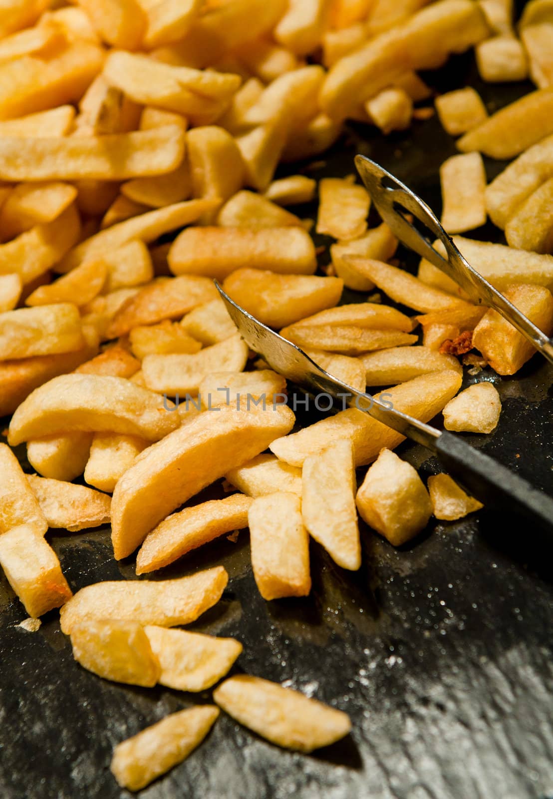 bunch of french fries on a black wooden board (shallow DOF)