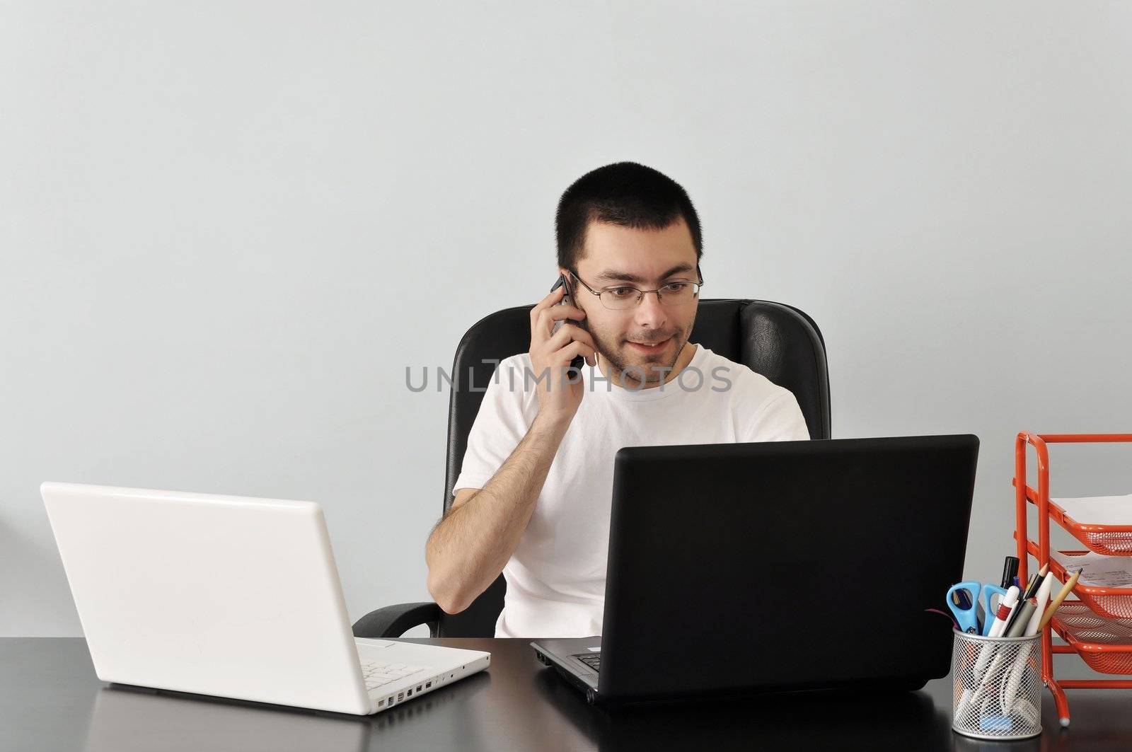 Young businessman working at his desk with two laptops