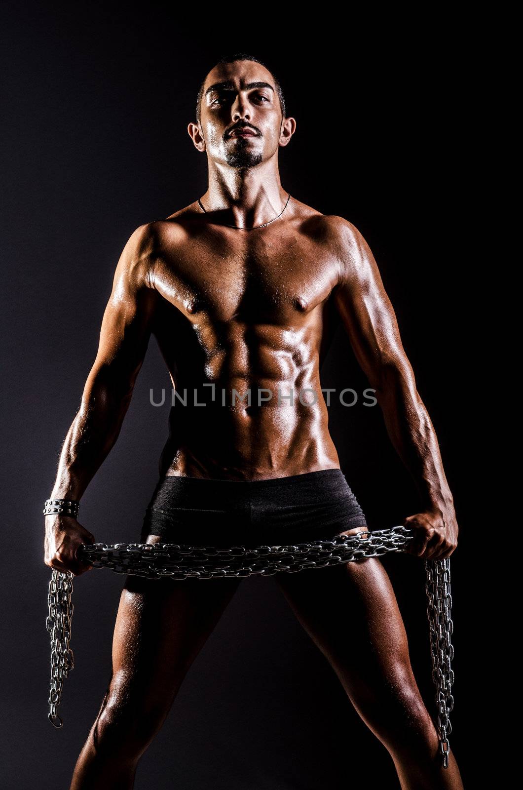 Bodybuilder with chains in dark